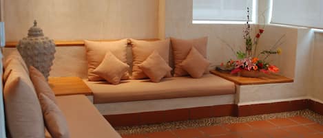 A cozy seating area with a cushioned bench, a small table, and a decorative vase with flowers.
