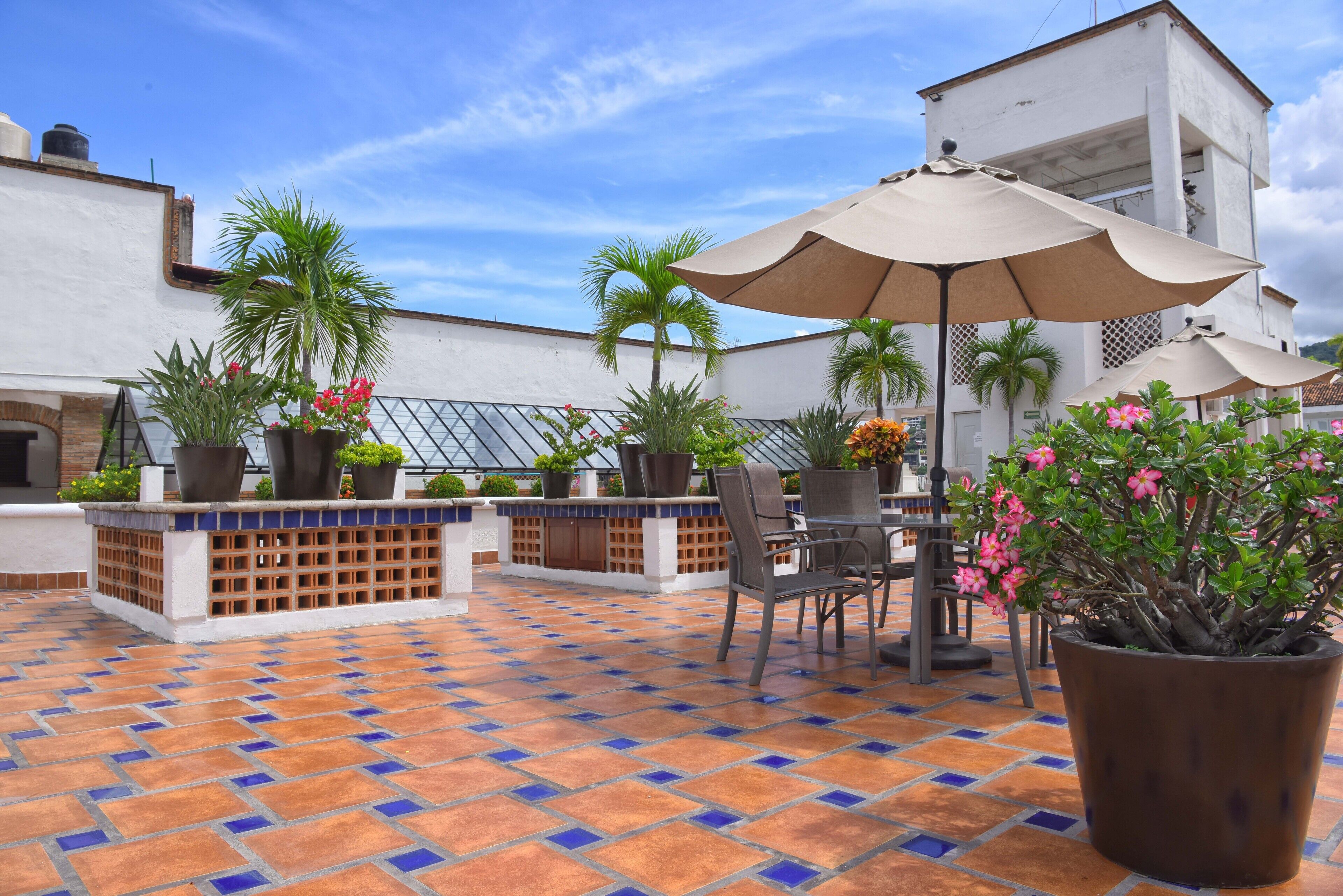 Une terrasse extérieure avec un sol carrelé, des sièges et des plantes en pot.