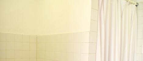 Une salle de bain avec des toilettes, un rideau de douche et des murs carrelés.