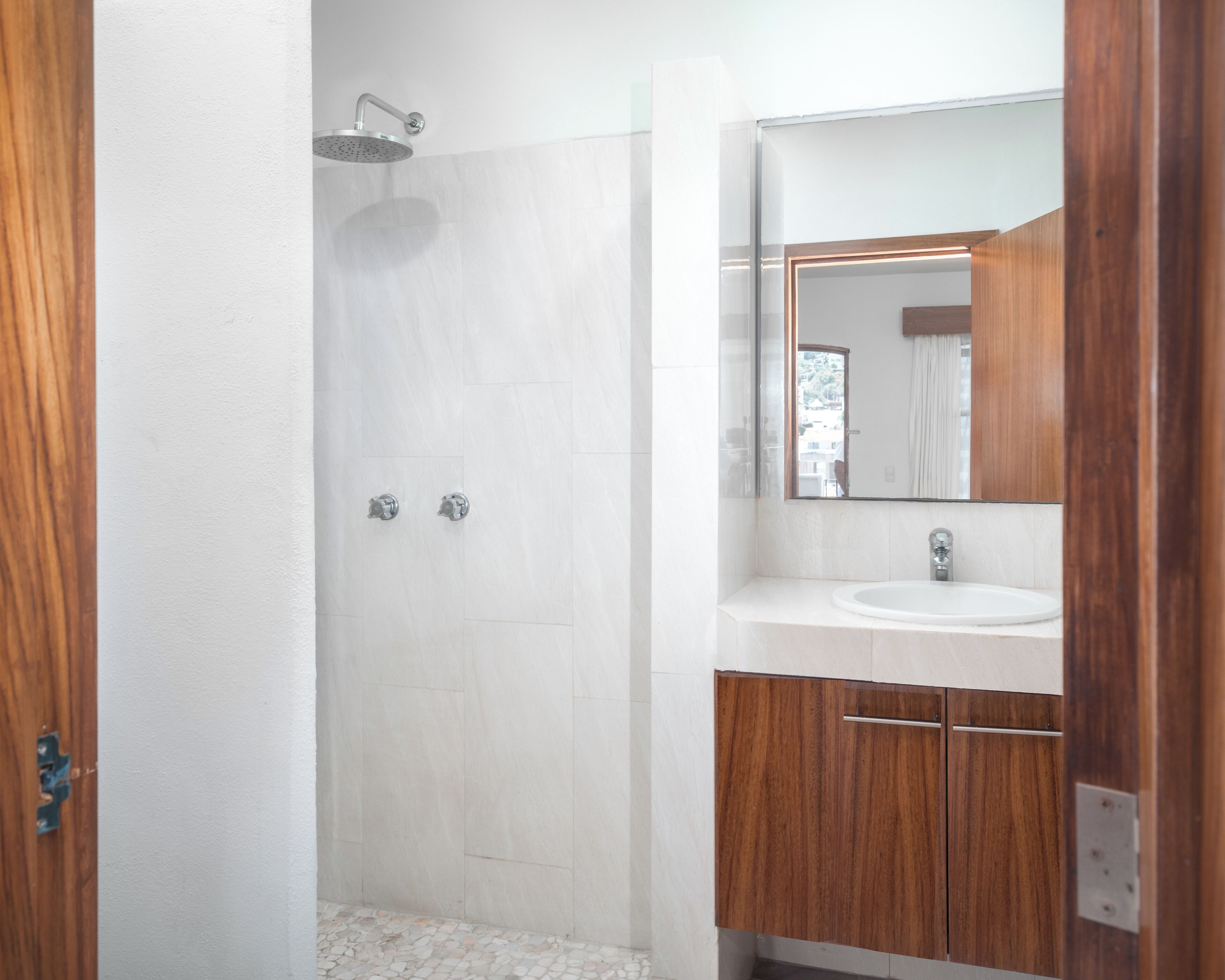 A bathroom with a shower, a sink, and wooden cabinets.
