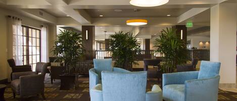 A lobby with several armchairs, a patterned carpet, and hanging pendant lights.
