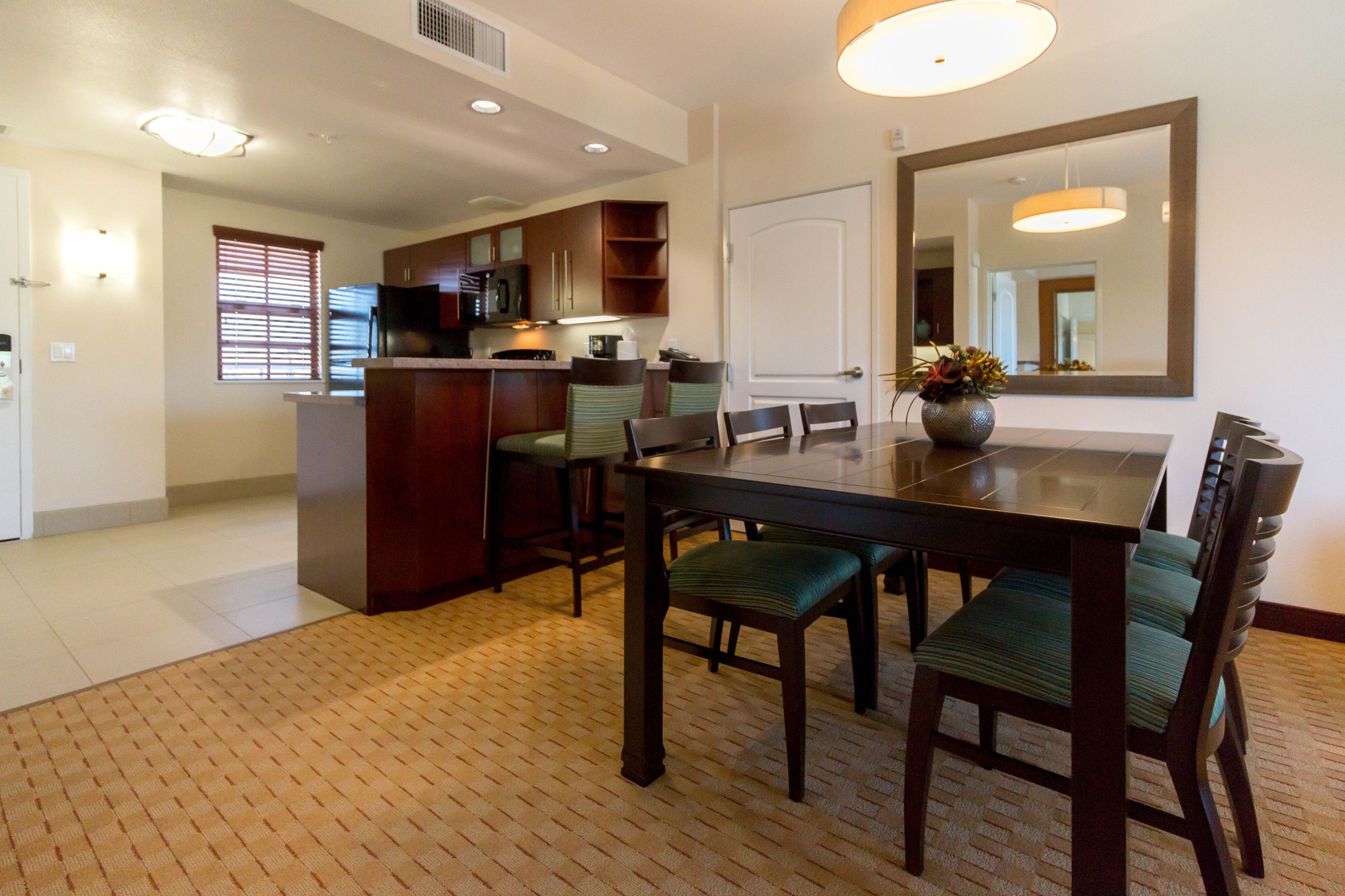 A dining area with a rectangular table, four chairs, and a large mirror on the wall.