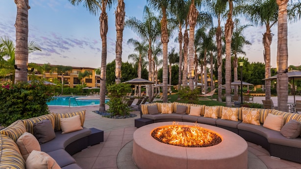 A poolside area with a circular fire pit surrounded by a curved seating area with striped cushions. - MarBrisa Carlsbad Resort (Carlsbad)