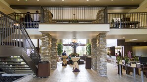 A spacious lobby with a central seating area, a staircase, and a second-floor balcony. - MarBrisa Carlsbad Resort (Carlsbad)