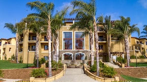 A multi-story hotel with a central entrance, palm trees, and a landscaped garden. - MarBrisa Carlsbad Resort (Carlsbad)