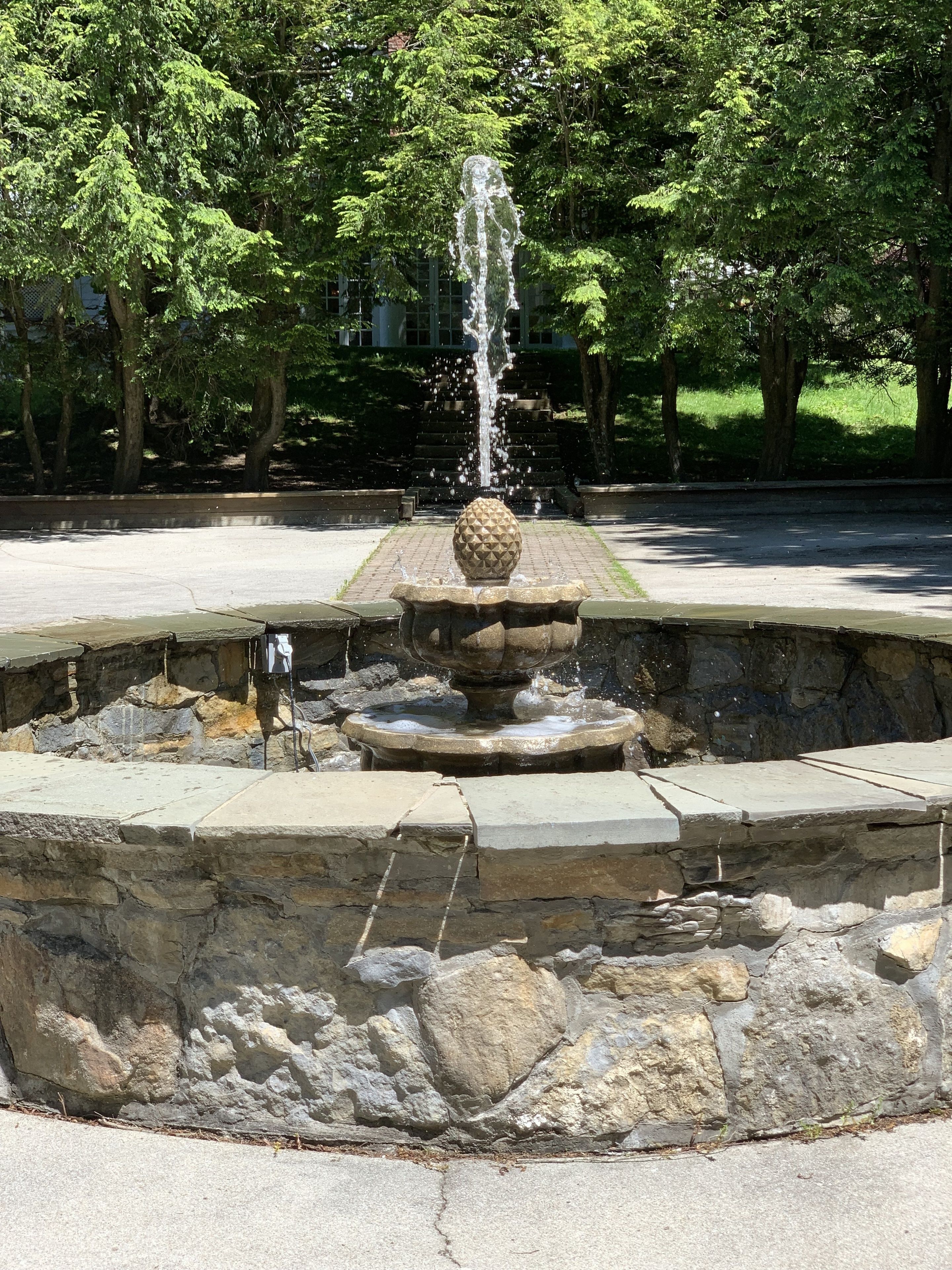A fountain with a spherical top, surrounded by stone steps and a stone wall.
