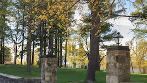 A stone gate with a lantern, surrounded by trees and a grassy area. - The Four Chimneys Inn (Bennington)