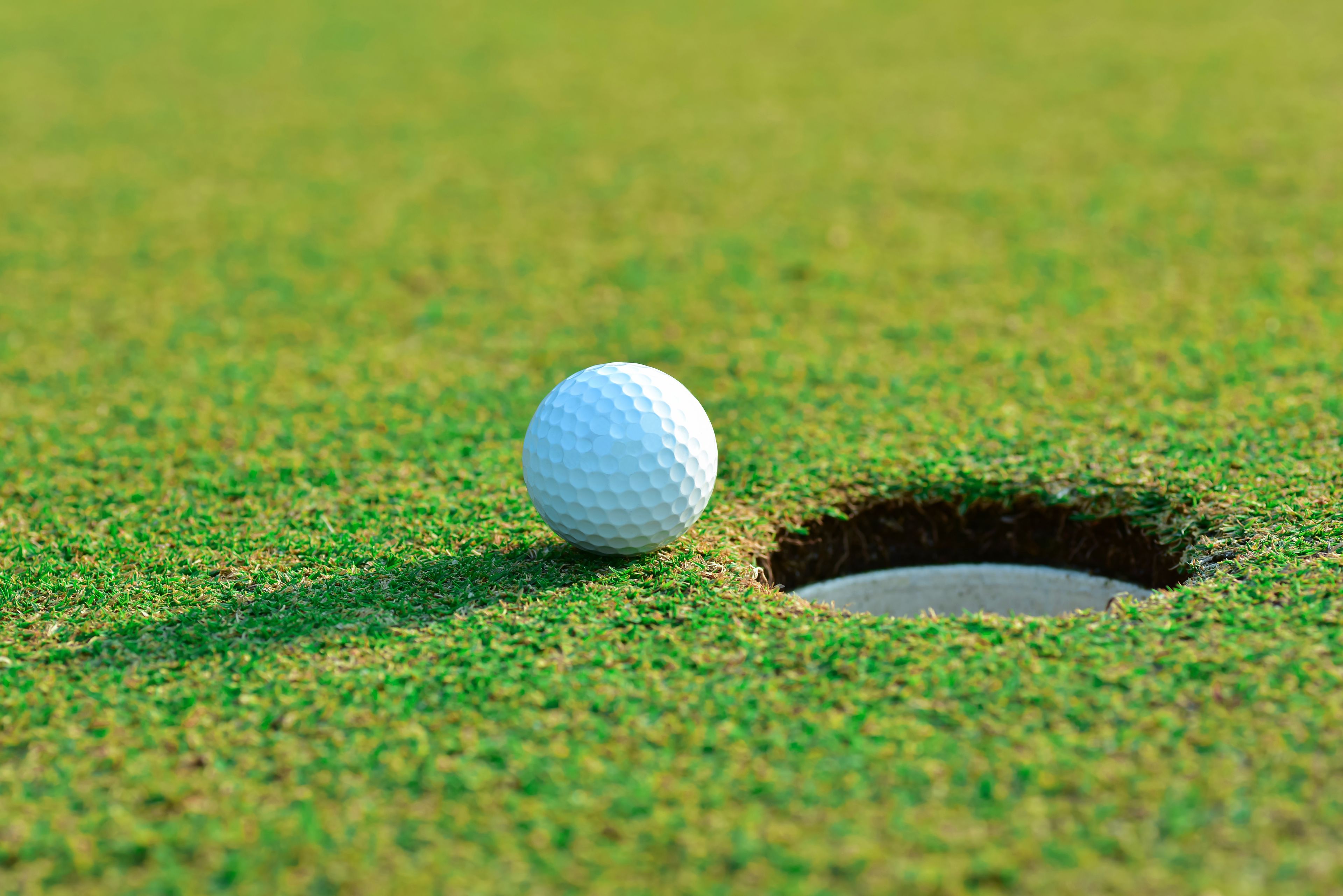 Een golfbal op een gazon met een hole.