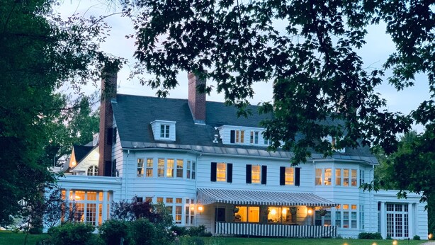 A large, two-story house with a wrap-around porch and multiple windows.