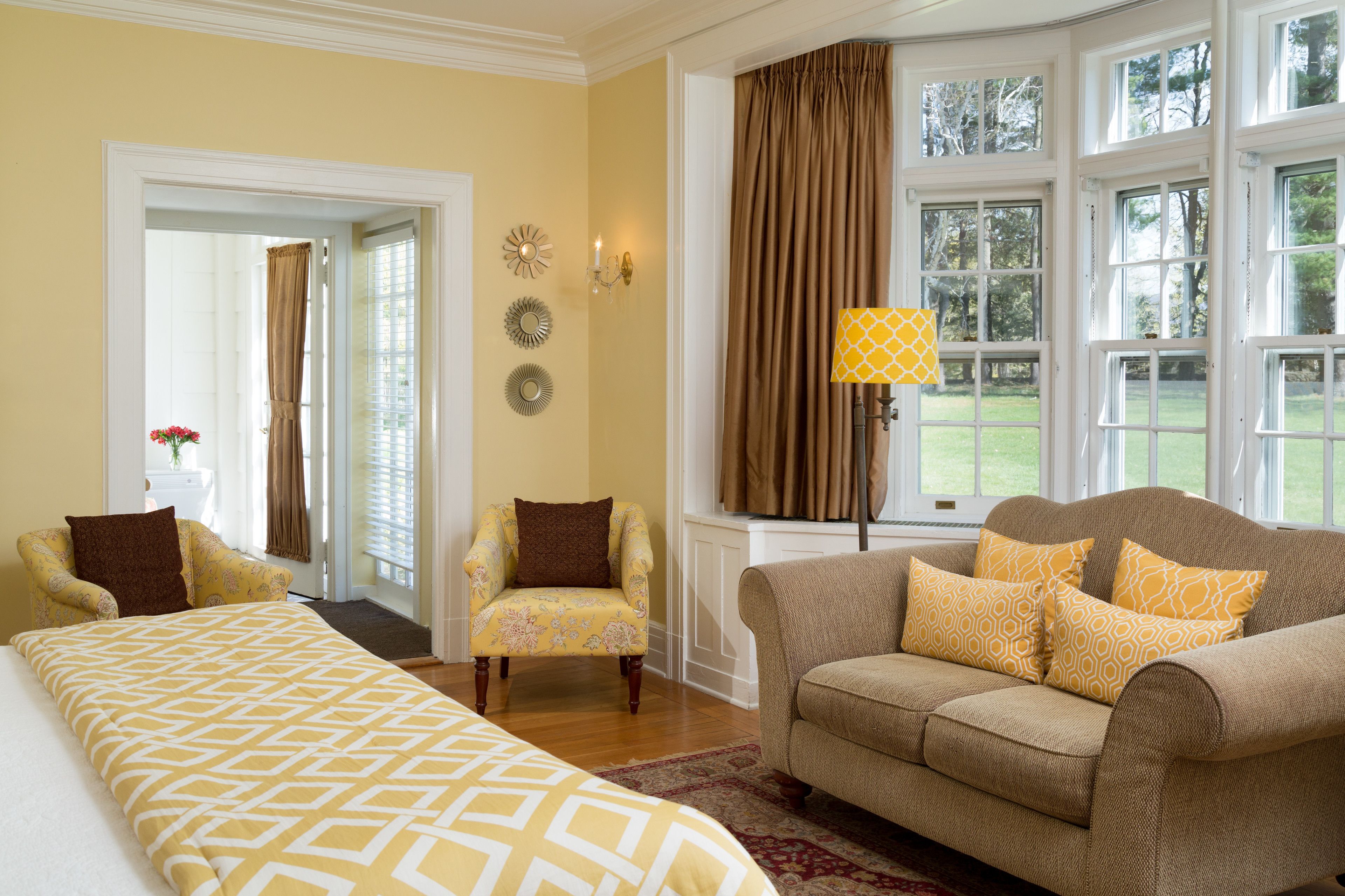 A hotel room with a bed, a sofa, a chair, and a window with curtains.