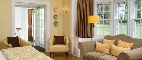 A hotel room with a bed, a sofa, a chair, and a window with curtains.