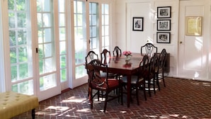 A dining room with a brick floor, large windows, and a chandelier. - The Four Chimneys Inn (Bennington)