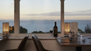 A table set for dining with a bottle of wine and glasses, overlooking a body of water. - Luccombe Hall Hotel (Shanklin)