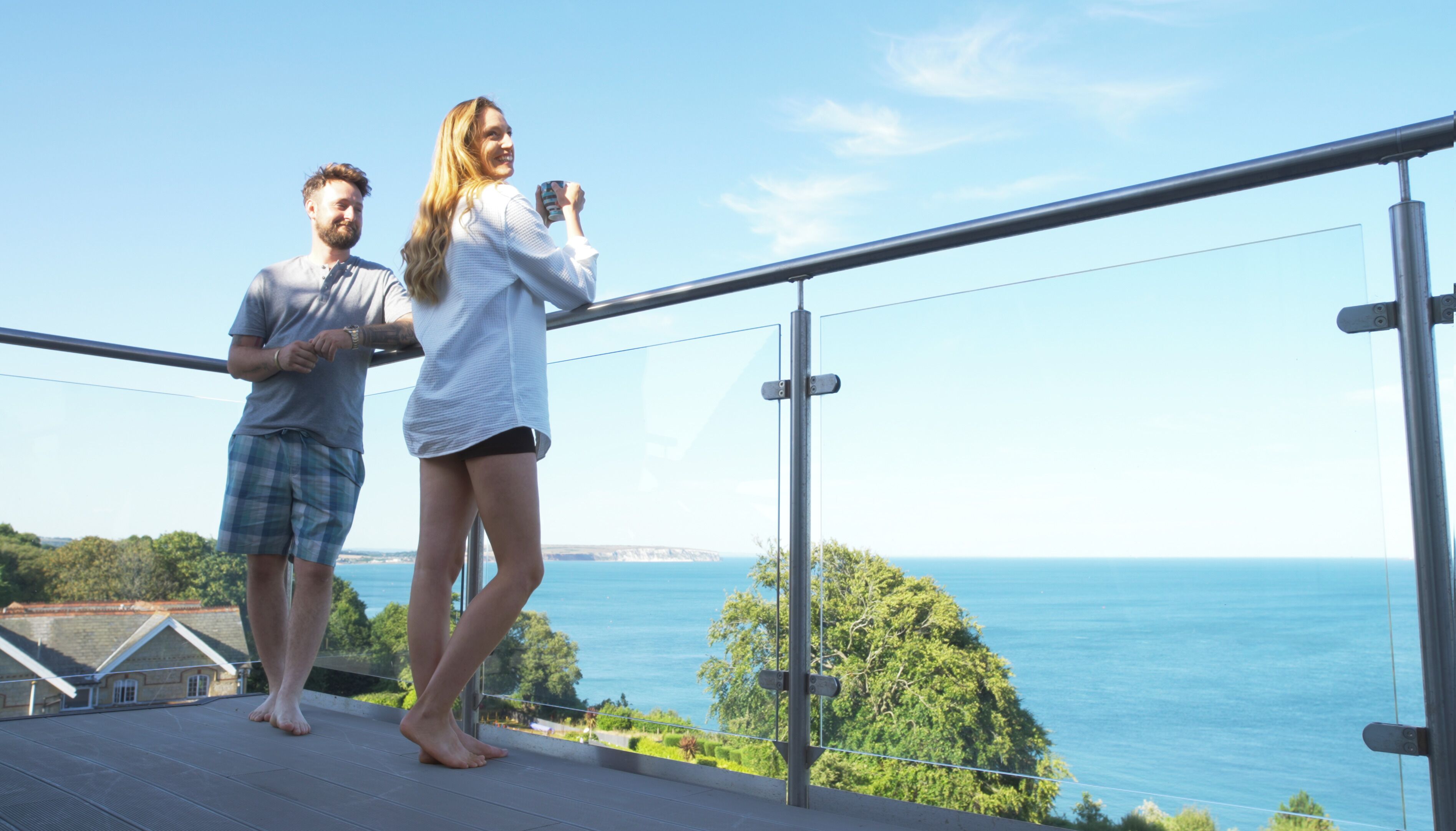 A balcony with a view of the sea and greenery.