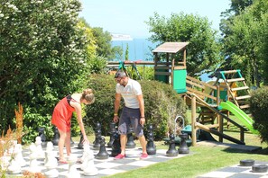 A chessboard set up outdoors with a wooden play structure in the background.