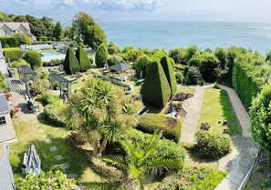 A landscaped garden with a pool, seating areas, and a gazebo overlooking a body of water. - Luccombe Hall Hotel (Shanklin)