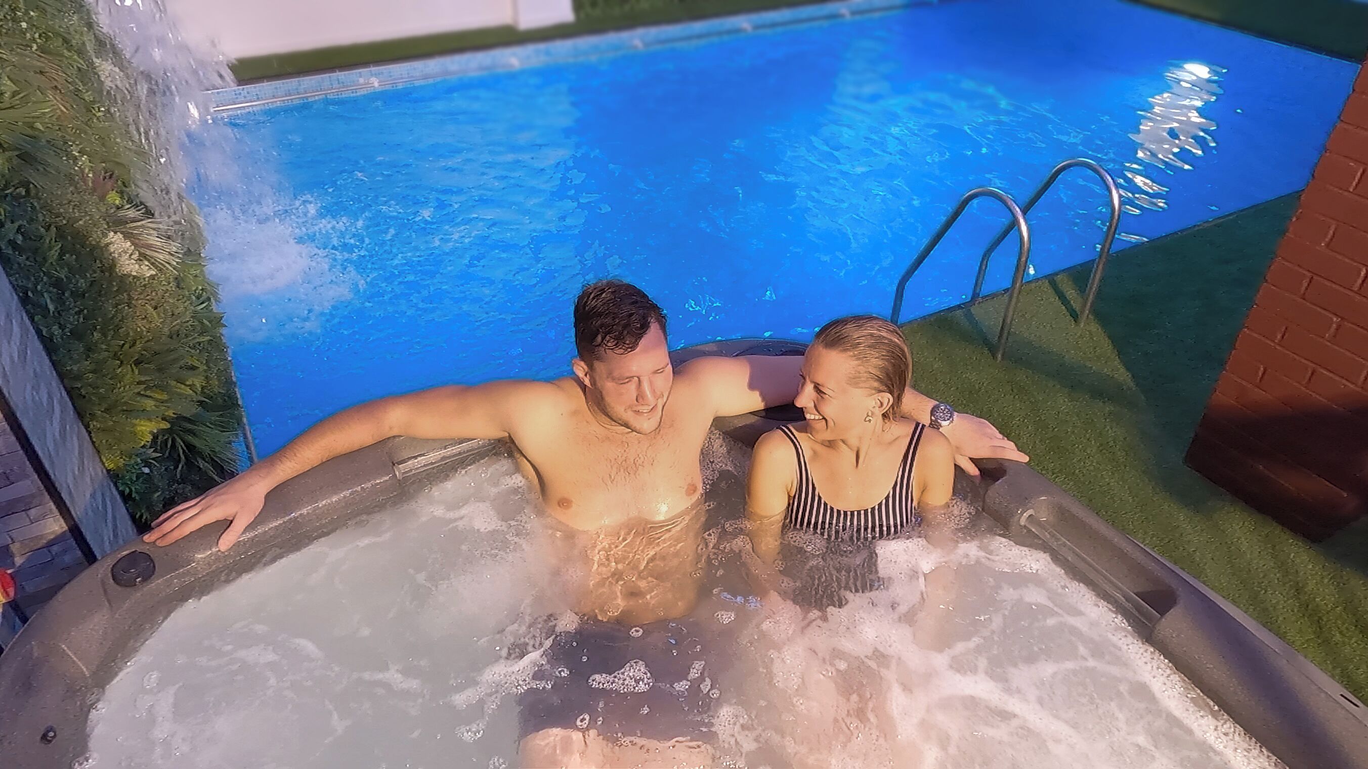 Una vasca idromassaggio con una piscina sullo sfondo.