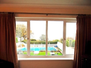 A room with a large window overlooking a swimming pool and a well-maintained garden.