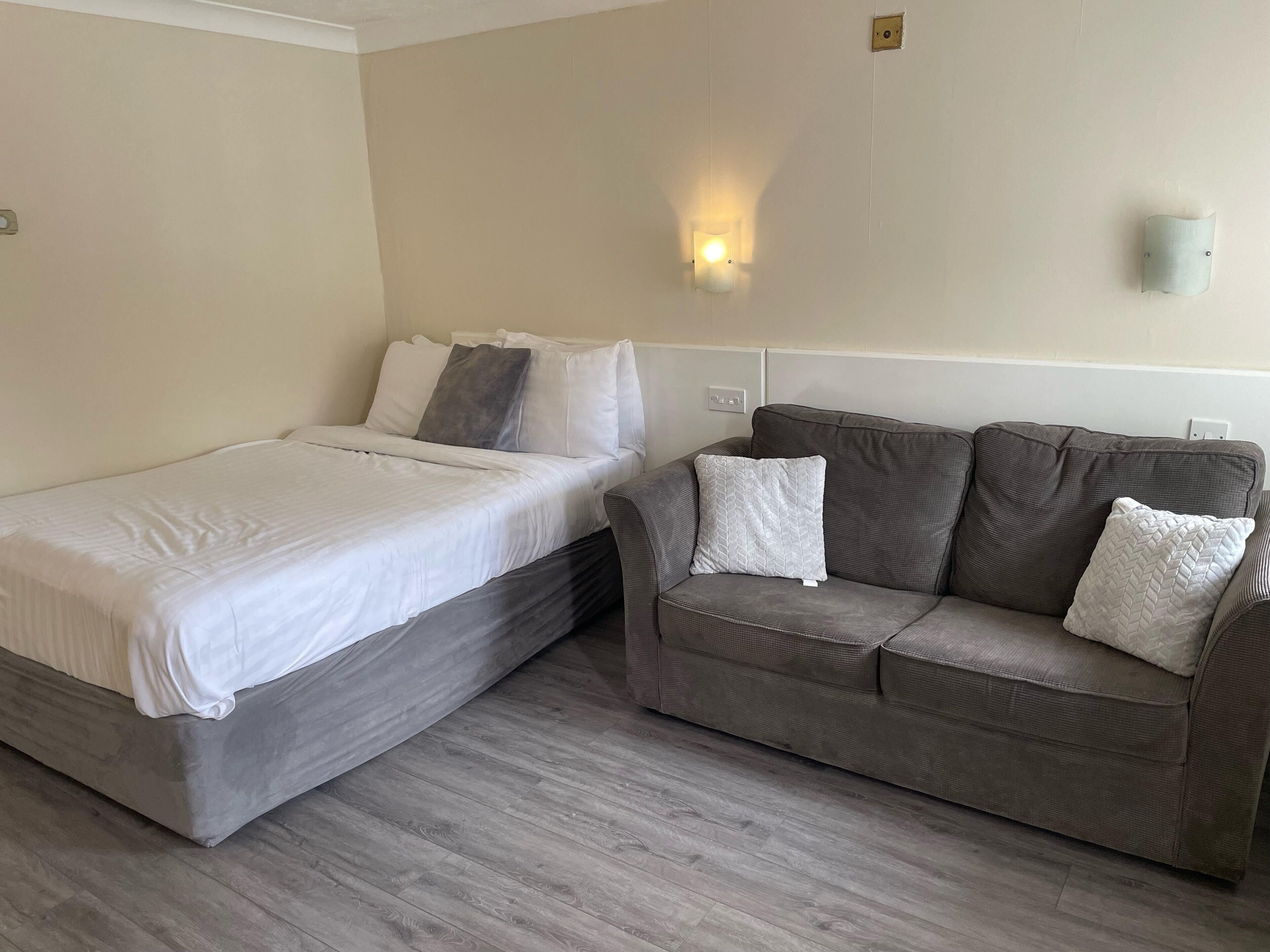 A bedroom with a bed and a grey sofa.