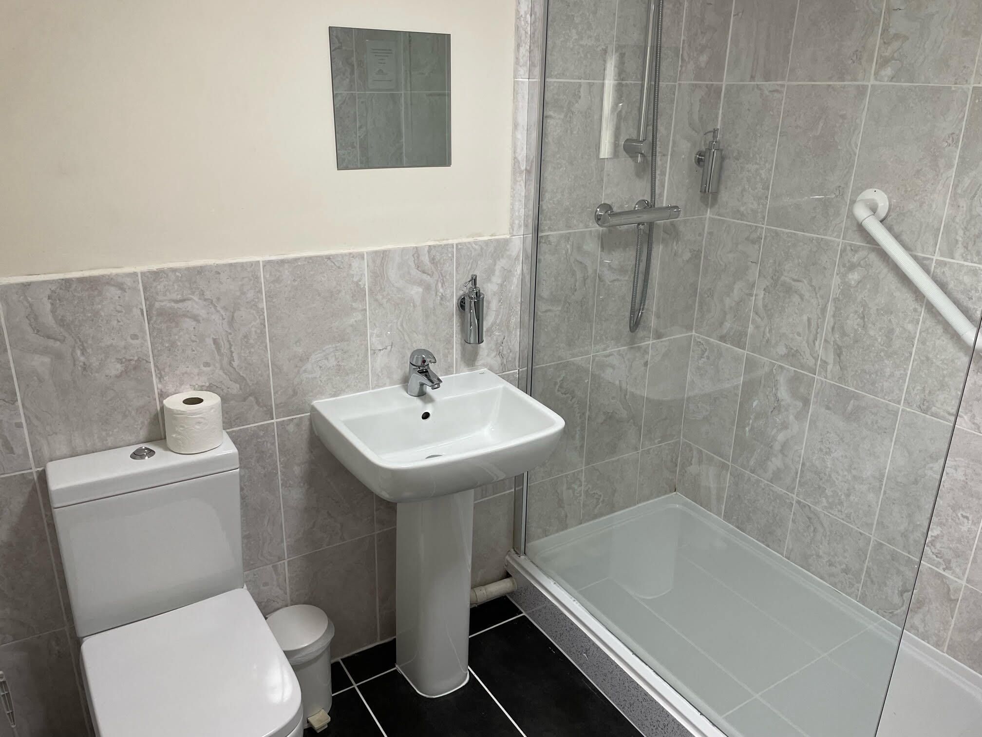 A bathroom with a toilet, sink, and glass shower enclosure.