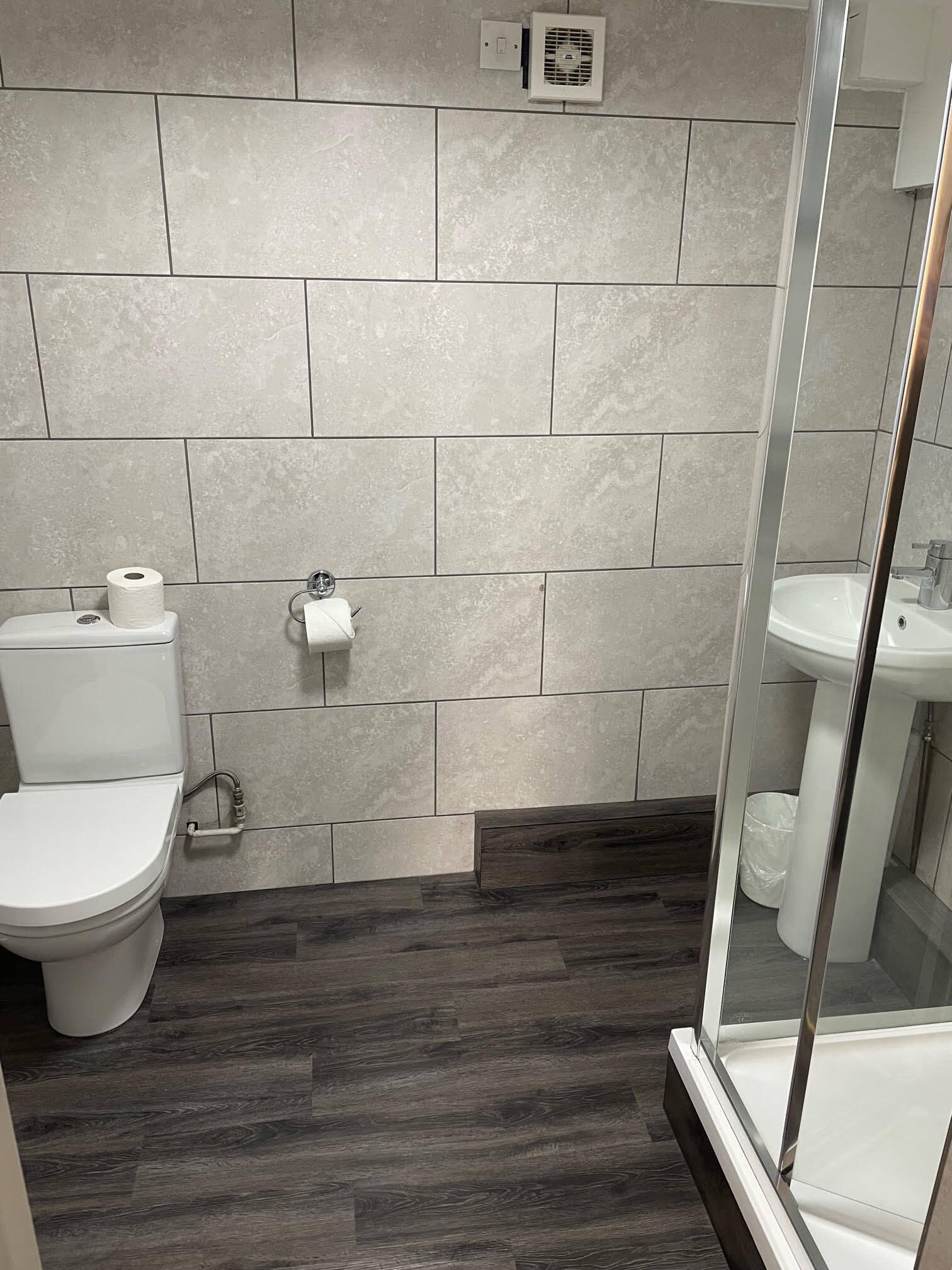 A bathroom with a toilet, a sink, and a shower area.