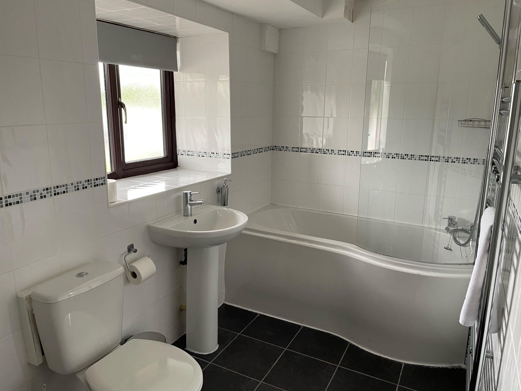 A modern bathroom with a white sink, toilet, and bathtub.