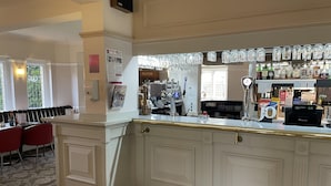 A bar area with a counter, bar stools, and a variety of bottles and glasses. - Mountain Park Hotel (Flint)