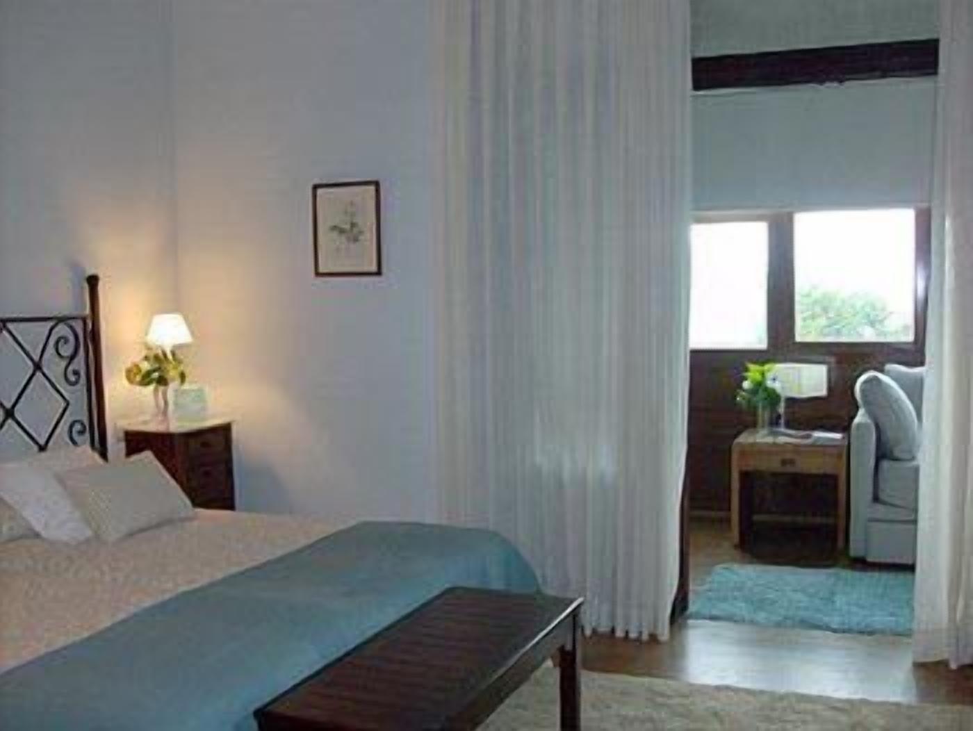 A bedroom with a bed, bedside tables, a desk, and a chair.