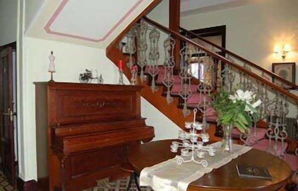 A staircase with ornate metal railings, a wooden cabinet, and a table with a vase of flowers.
