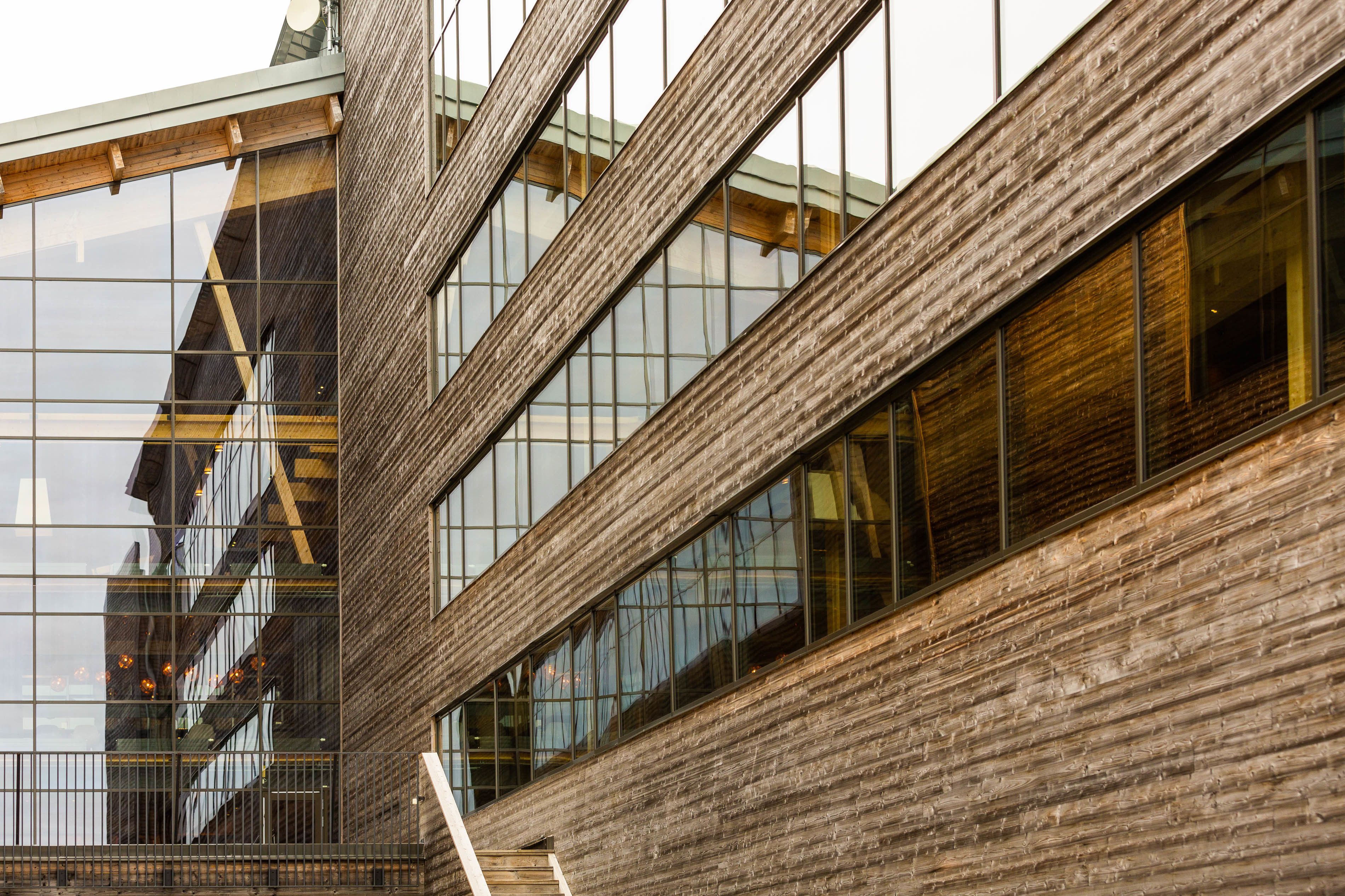 A modern building with large reflective windows and a wooden facade.