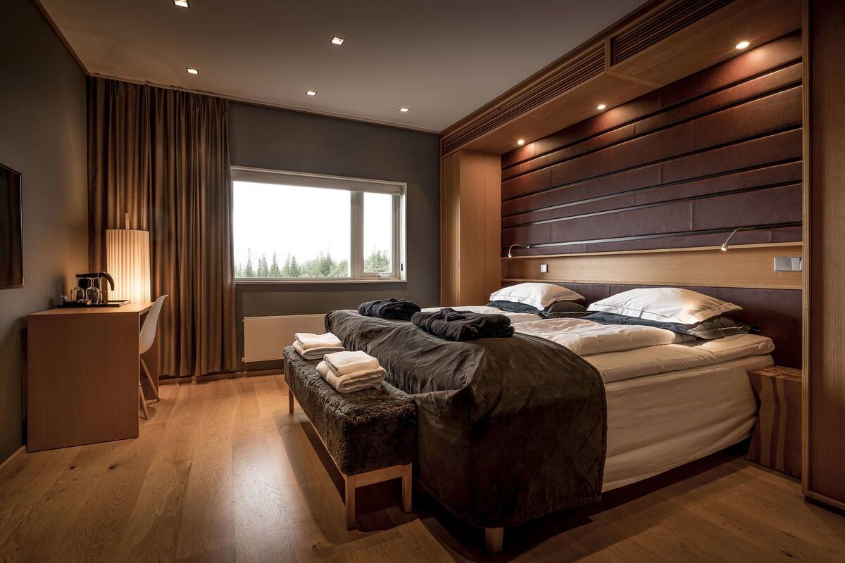 Ein modernes Schlafzimmer mit einem großen Bett, einer Bank, einem Schreibtisch und einem Fenster.