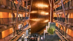 A spacious indoor atrium with multiple levels, wooden beams, and a central seating area with sofas and tables.