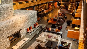 A spacious lounge area with a stone fireplace, multiple seating arrangements, and a bar in the background.