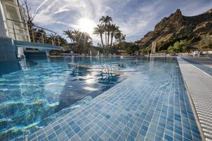 Una piscina cubierta, una piscina al aire libre, sombrillas, tumbonas