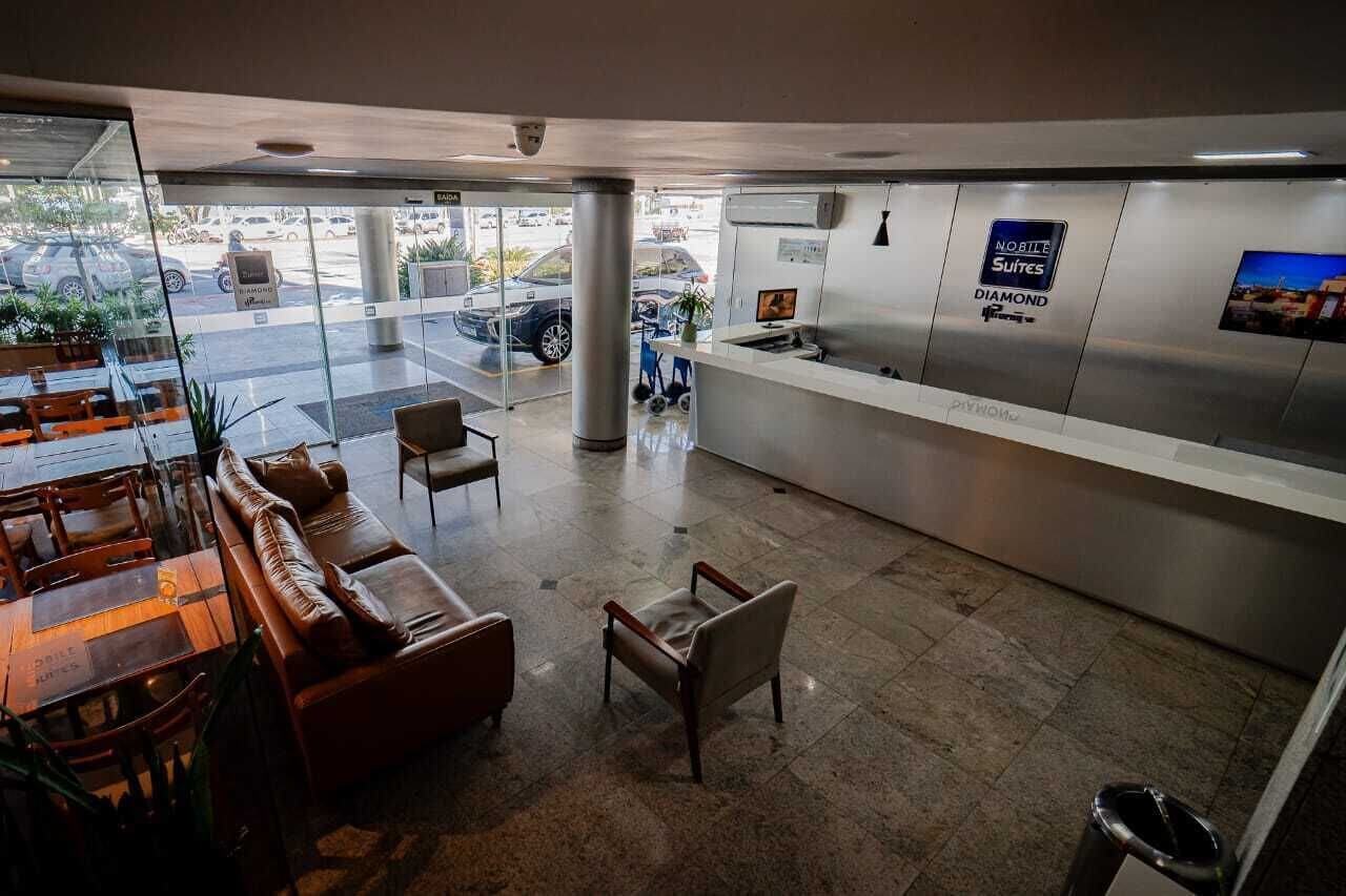 Um saguão de hotel com balcão de recepção, área de estar e vista para o estacionamento.