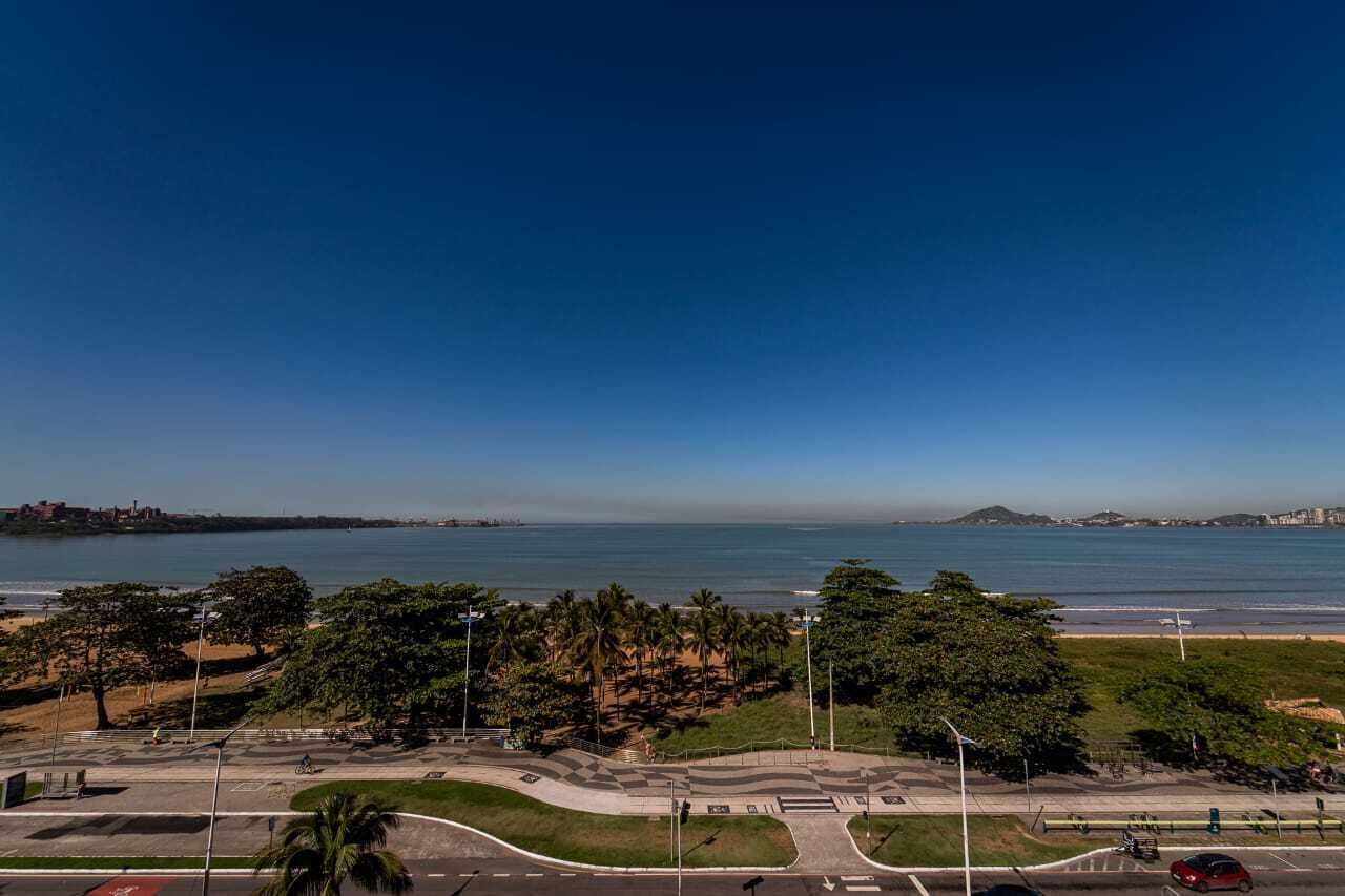 A coastal road with a beach and palm trees in the distance.
