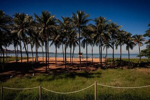 A beach with palm trees, a lifeguard tower, and a fenced area. - Nobile Suites Diamond (Vitoria)