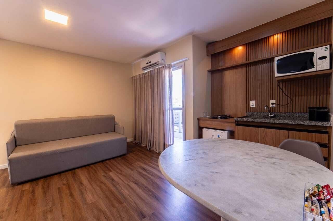 A modern room with a sofa, a dining table, a microwave, and a built-in kitchen counter.