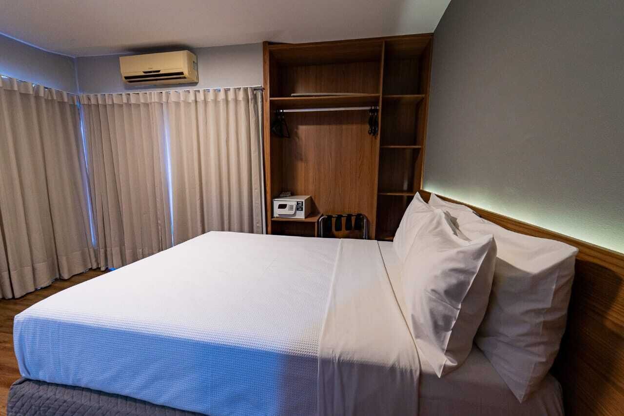 Habitación de hotel con cama, armario, escritorio y aire acondicionado.