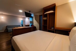 A hotel room with a bed, a wooden nightstand, a TV, a desk, and a built-in wardrobe.