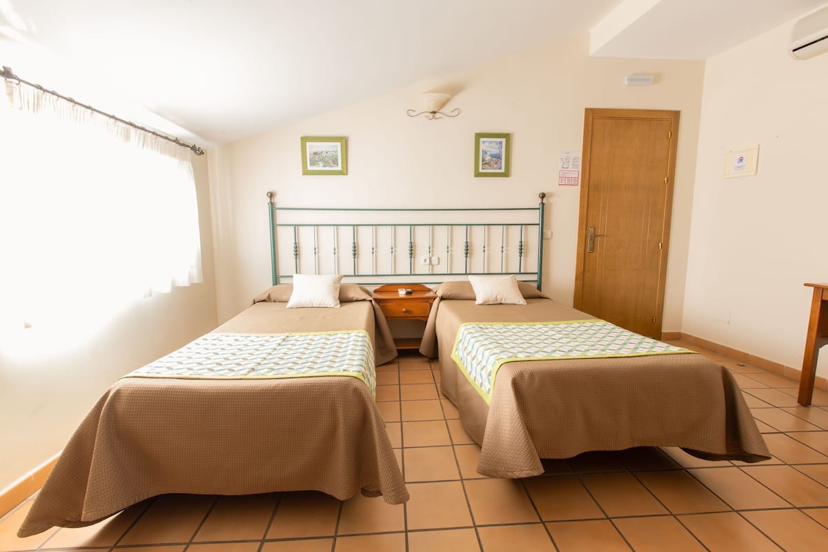 Ein Zimmer mit zwei Betten, einer Holztür und einem kleinen Tisch.