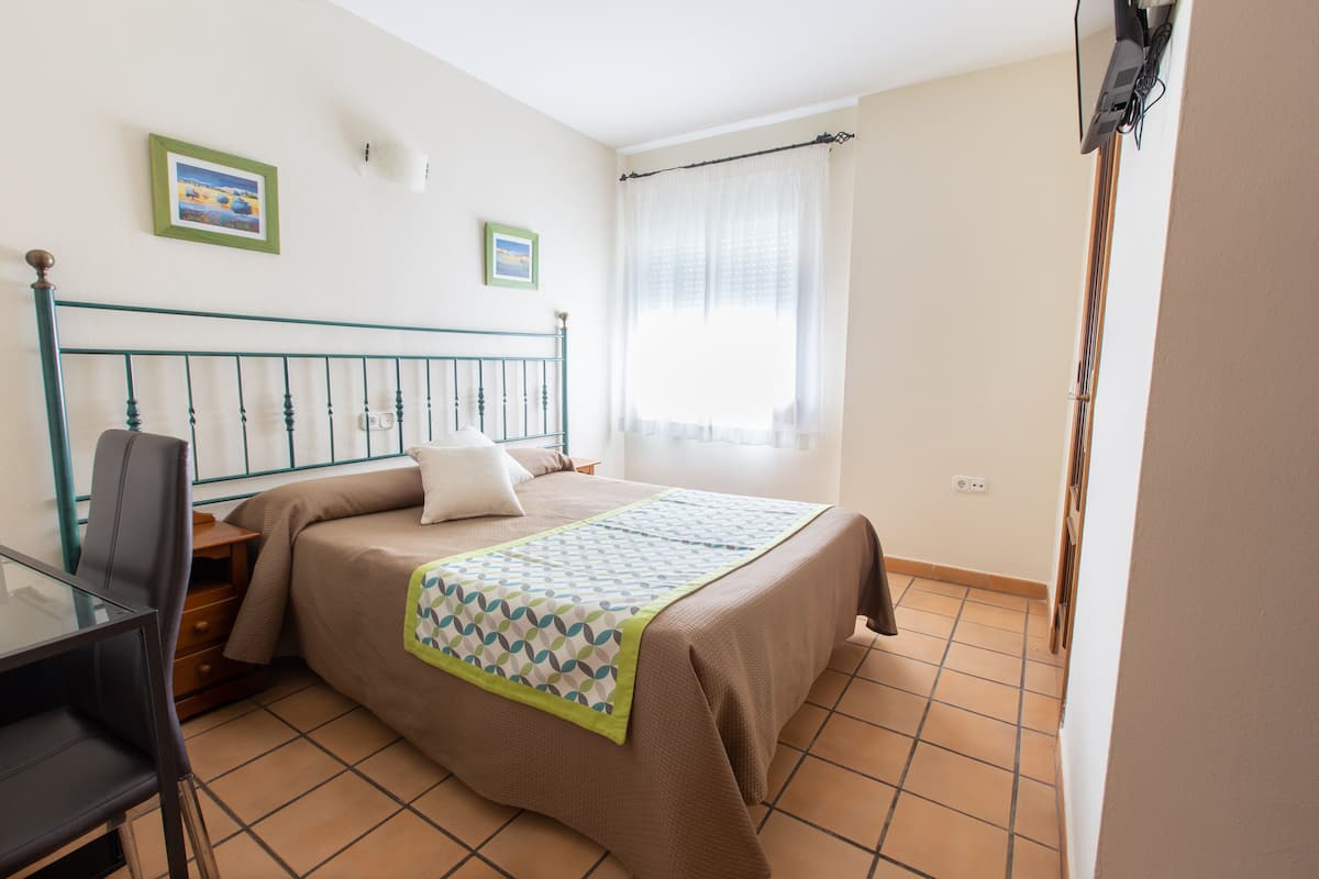 Ein Schlafzimmer mit einem Bett, einem Schreibtisch und zwei gerahmten Bildern an der Wand.