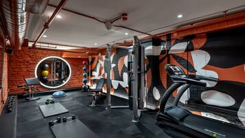 Un gimnasio con equipo de ejercicio, un espejo y una pared con un diseño abstracto grande.