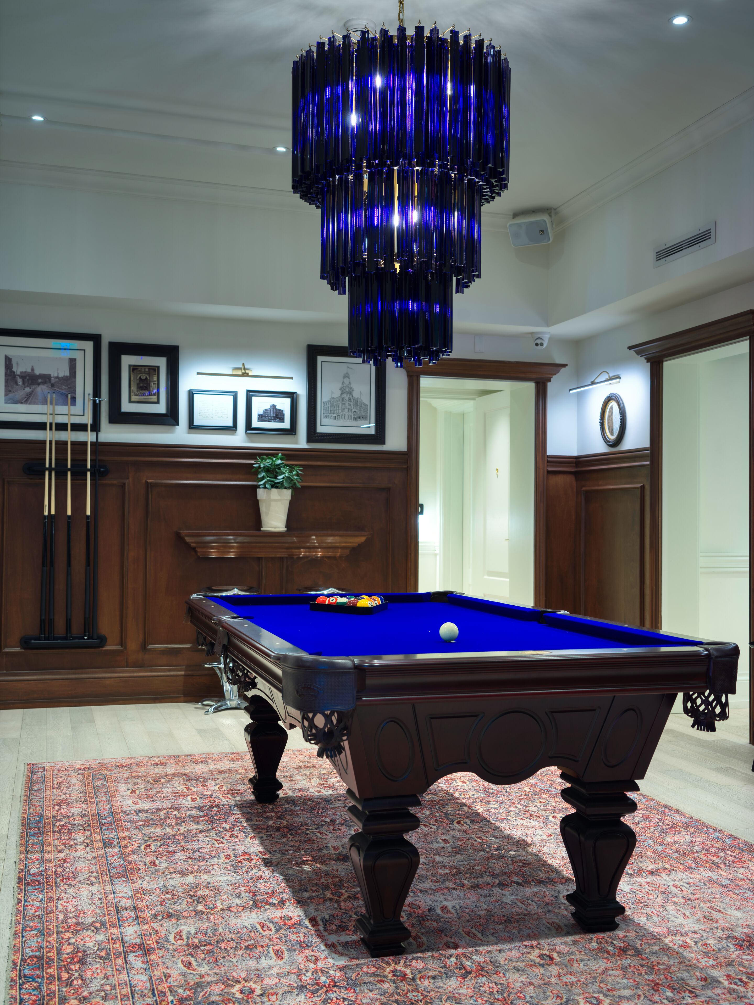 A pool table with a blue felt surface, surrounded by a patterned carpet.