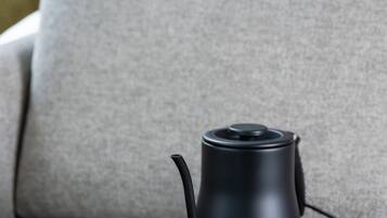 Un plateau noir avec une théière et deux tasses, posé sur un canapé gris.
