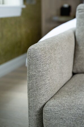 Un primer plano de una tela texturizada, probablemente parte de un sofá o sillón, en un color neutro.