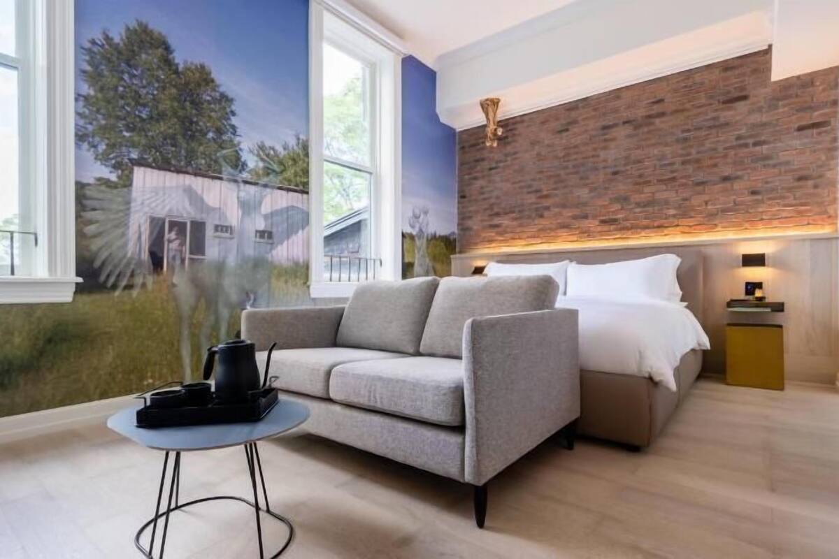 Un salon moderne avec un canapé, une table basse, un mur en briques apparentes et une fresque murale.