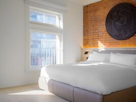 Een moderne slaapkamer met een groot bed, een wand van baksteen en een raam met jaloezieën.
