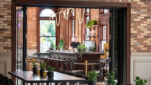 A restaurant with brick walls, wooden furniture, and potted plants.