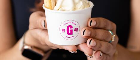 A person holding a cup with a churro and a spoonful of ice cream.